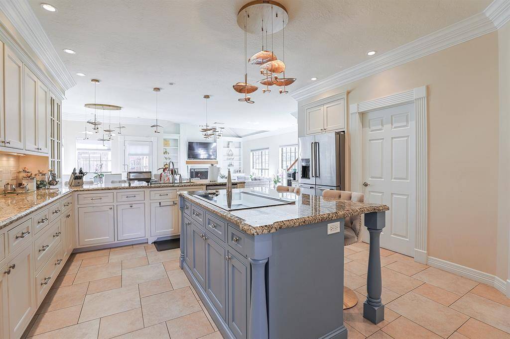 A chef's dream kitchen with an oversized island, granite countertops, custom cabinetry, and high-end stainless-steel appliances. The open-concept layout seamlessly connects to the living and dining areas, making it ideal for entertaining.