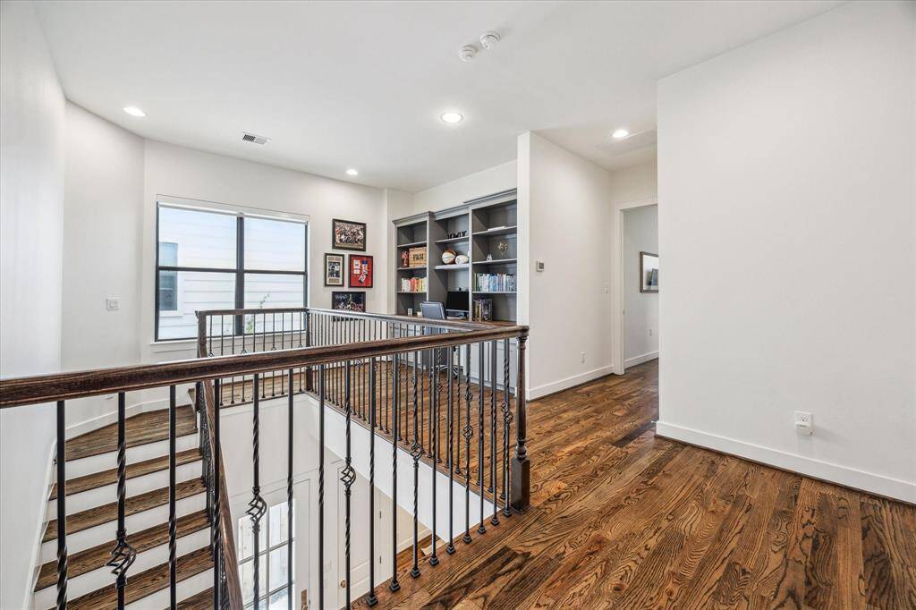 A view coming up the staircase leading to a landing area with a custom built bookcase and desk.