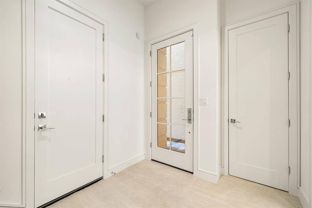 This entryway features a modern door with glass panels, offering natural light! The space is bright with neutral walls and floors, providing a clean and welcoming first impression!