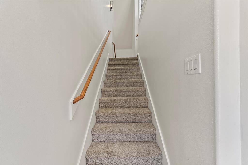 Soft carpet underfoot and clean, neutral tones make your stairway feel both cozy and bright. A wood-accented handrail and updated sconce lighting add subtle touches of warmth and style as you transition between floors.