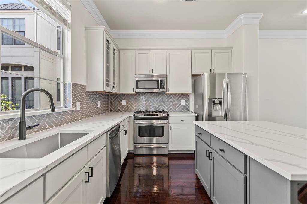 Crisp white cabinetry, quartz countertops, and a herringbone tile backsplash bring a modern edge to your kitchen, while stainless steel appliances—including a gas range—add everyday function and style. The layout is ideal for cooking, entertaining, and staying connected to your guests in the open living space.