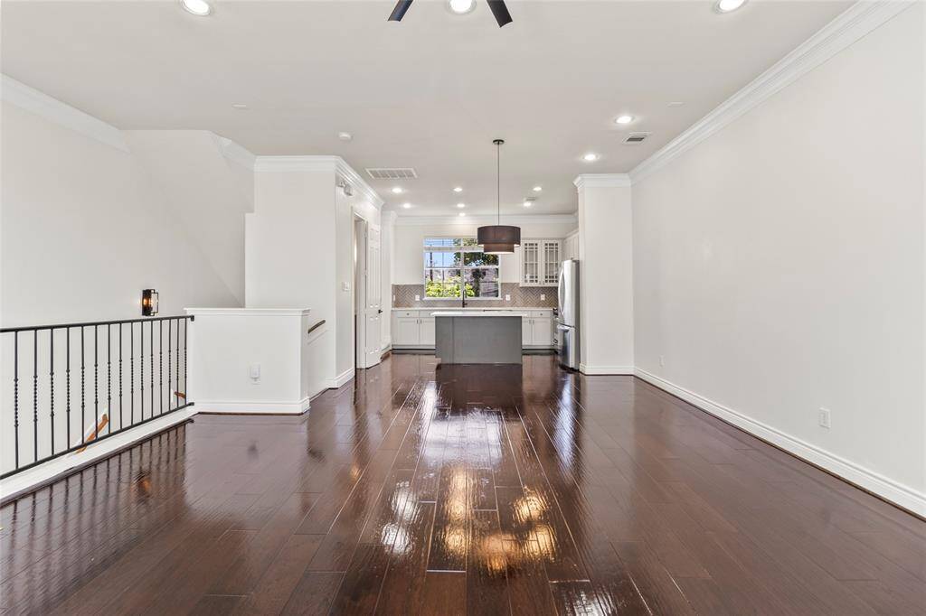 Wide plank wood floors stretch throughout your open living space, setting a warm and polished foundation for modern everyday living. The layout flows effortlessly from the living area into the kitchen, with crisp white walls and recessed lighting creating a bright, airy vibe. Whether you're relaxing, working from home, or entertaining, this space offers the versatility to suit your lifestyle.