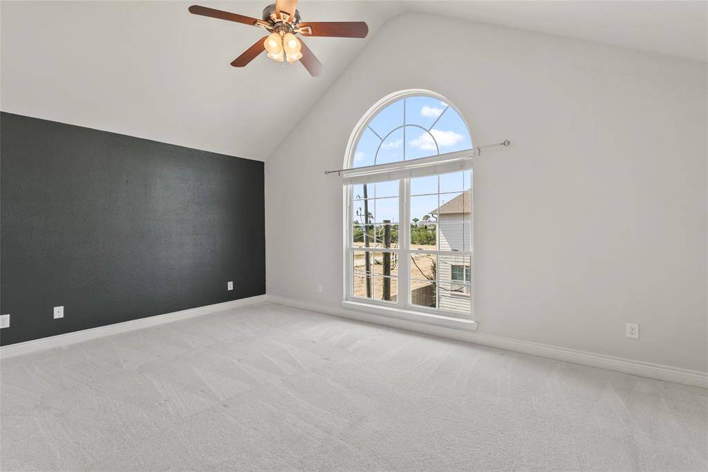 Enter your primary retreat showing you this space without virtual staging. This space is open and serene thanks to the high ceilings and striking arched window that floods the space with natural light. A rich accent wall brings just the right amount of depth and drama.