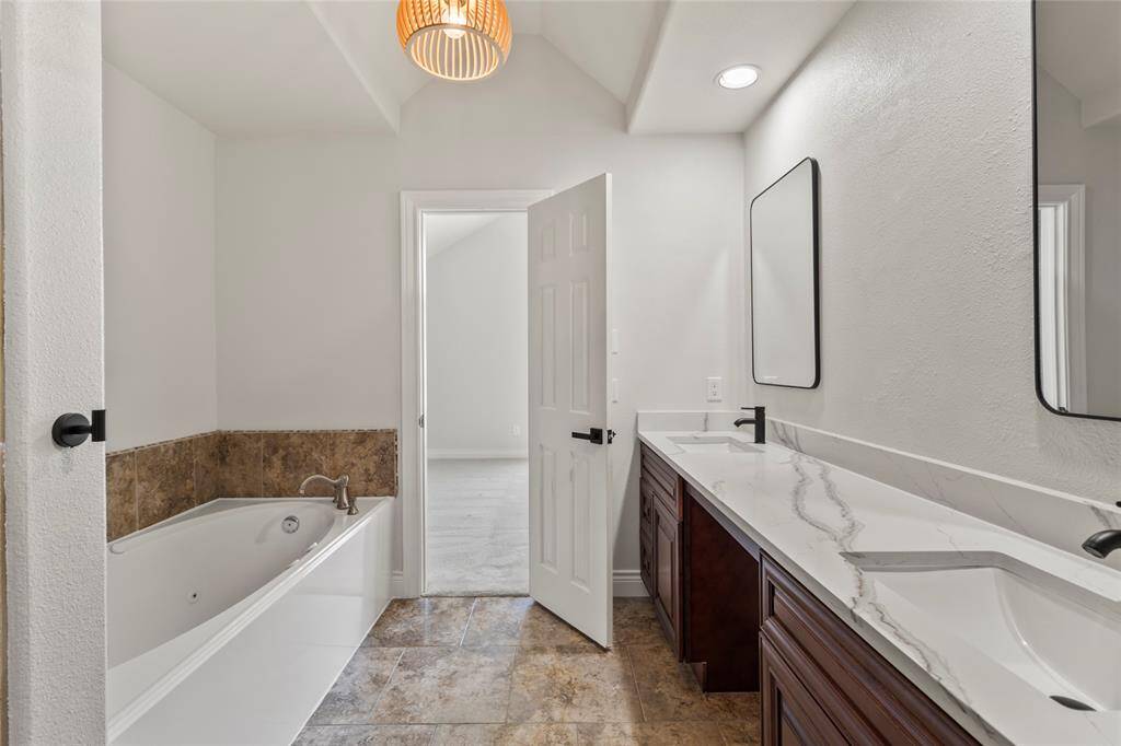 Warm tones and elegant finishes bring a spa-like feel to your en-suite bath, featuring a deep soaking tub, dual vanities with marble-look counters, and updated lighting. The spacious layout offers comfort and function, making everyday routines feel like a retreat.