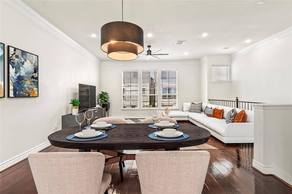 Sunlight fills your spacious living area through a wall of windows, bouncing beautifully off rich, glossy wood floors. Recessed lighting, crisp white walls, and crown molding give the space a modern yet timeless feel. Whether you're hosting friends or relaxing at the end of the day, this room offers the flexibility to make it your own.