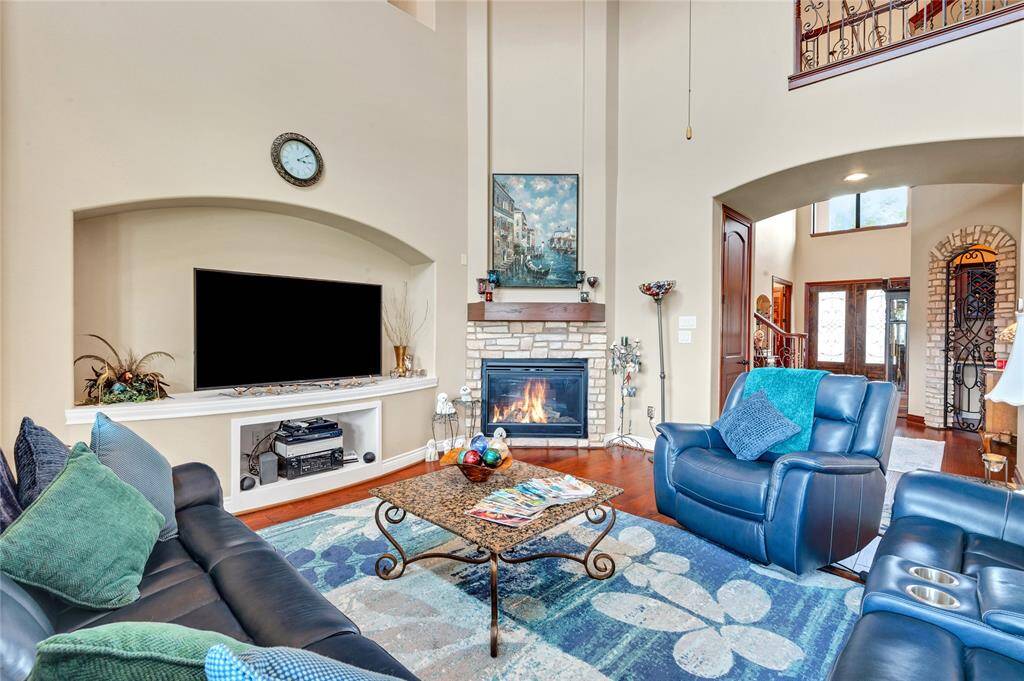 This inviting family room features vaulted ceilings, a cozy fireplace, and a large TV nook. Decorative elements and natural light create a warm, welcoming atmosphere.
