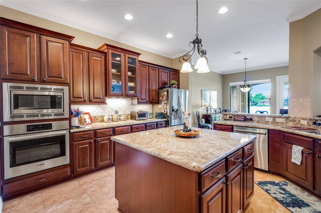 A large central island with granite countertops. It offers ample storage and workspace, complemented by elegant pendant lighting and an open view to the family area.