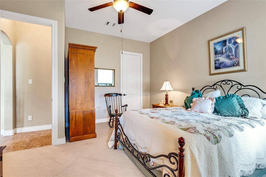 This  first floor guest bedroom features a ceiling fan, neutral walls, and carpet flooring. This guest bedroom has its own bathroom.