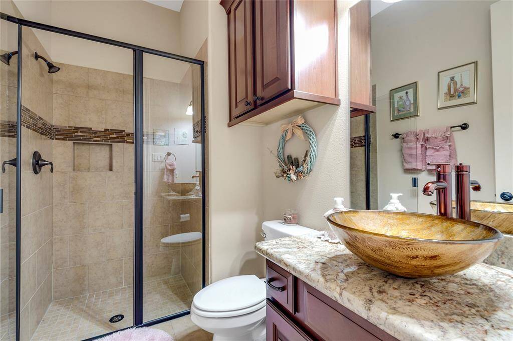 This guest bathroom features a granite countertop with a sink and a large mirror. A glass door with blinds leads access to the back patio.