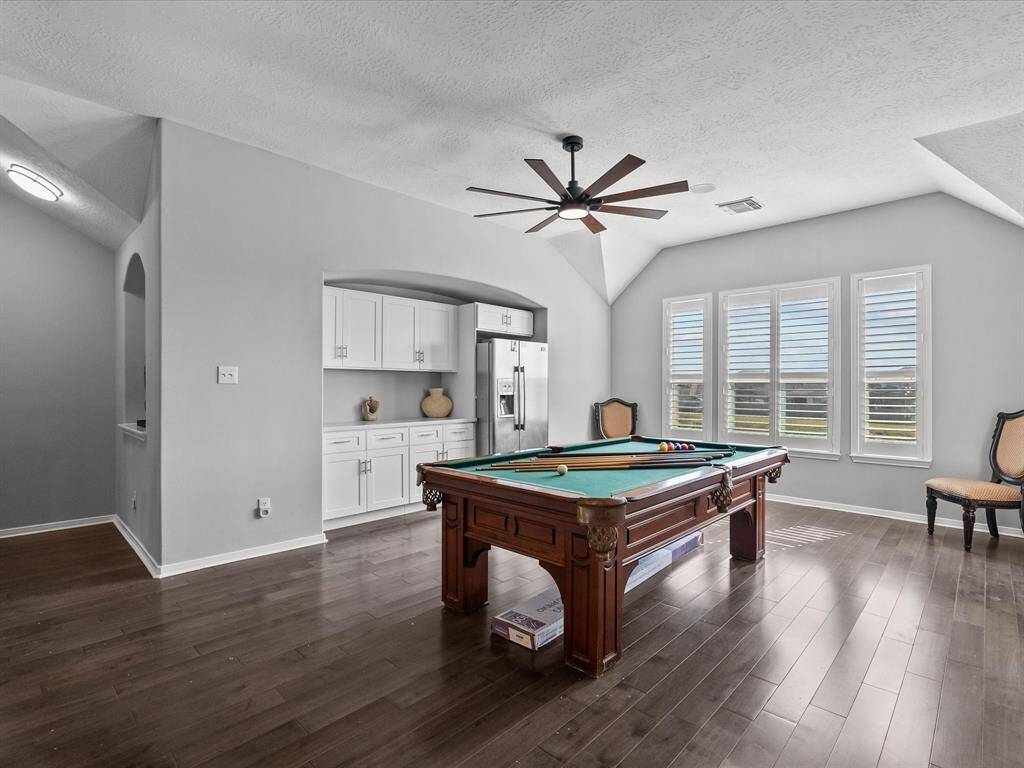 Upstairs game room features a convenient dry bar with a built-in refrigerator—perfect for entertaining. Pool table and refrigerator included