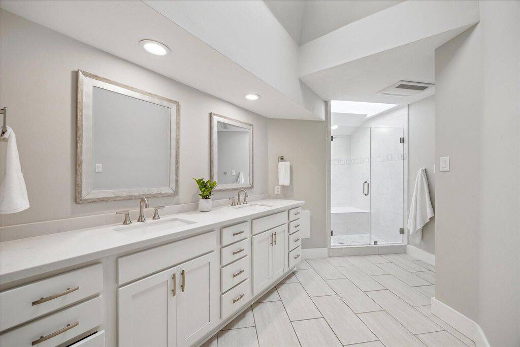 Bathed in natural light from the overhead skylights, the ensuite offers abundant counter space, thoughtful storage, and a private shower retreat complete with a built-in bench.