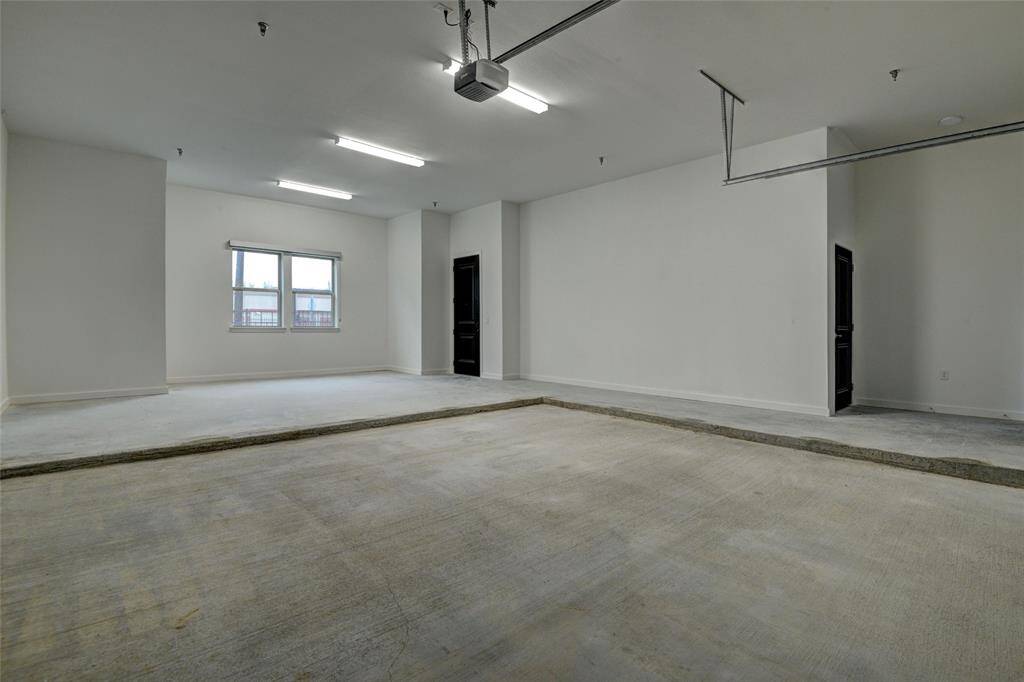 Large oversized two-car garage featuring a landing for trash cans, bikes, and more. It also includes a spacious walk-in storage room.