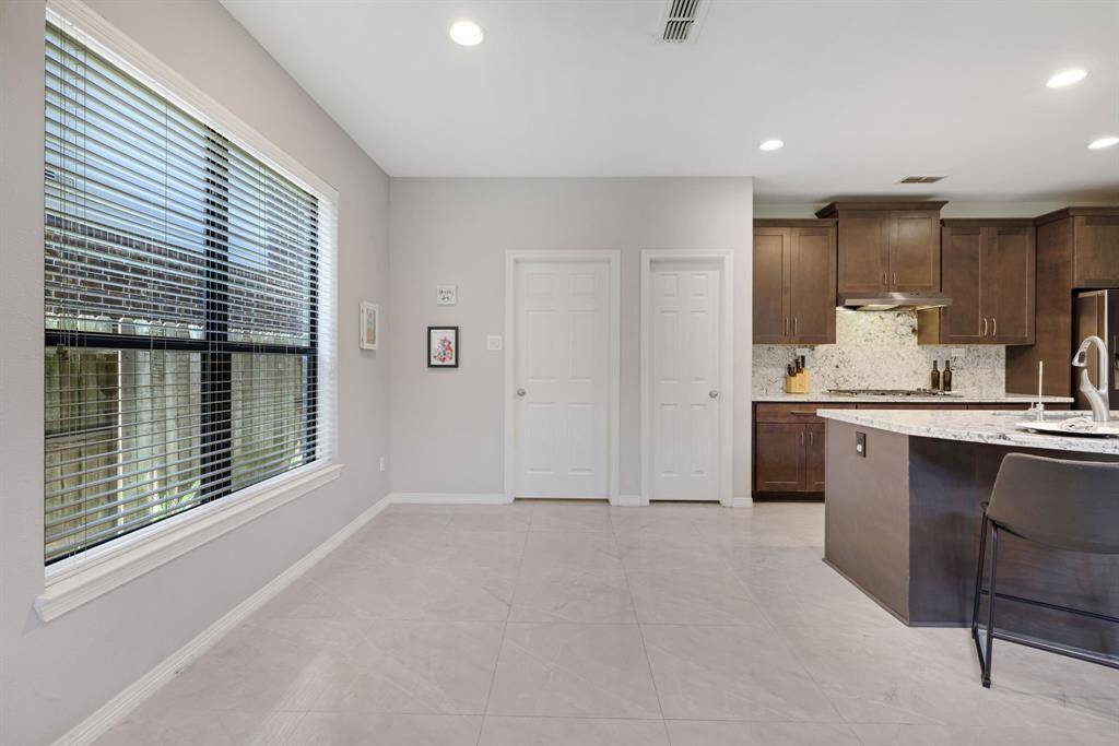 Breakfast area is located just off the kitchen island with doors leading to walk in-pantry and utility room