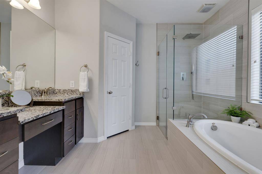 Primary en suite bath featuring granite counters, two sinks, and separate shower/tub.