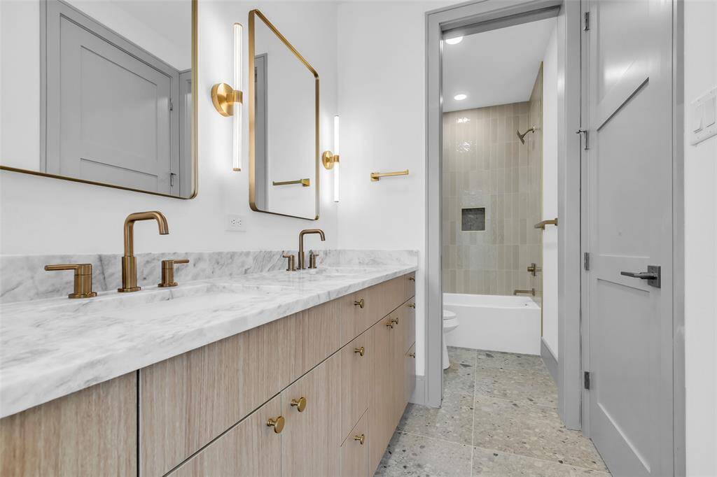 The common bathroom shared by the guest bedrooms includes double sinks and a tub-shower combo.