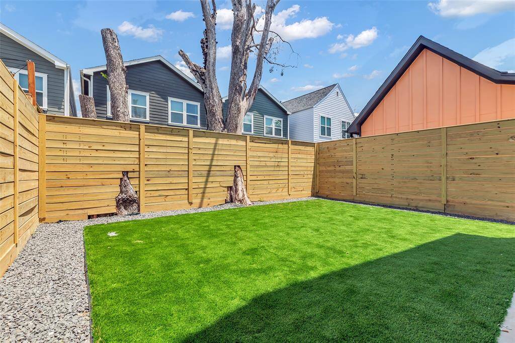 A full view of the cozy backyard, fully enclosed by a tall wooden fence for added privacy.