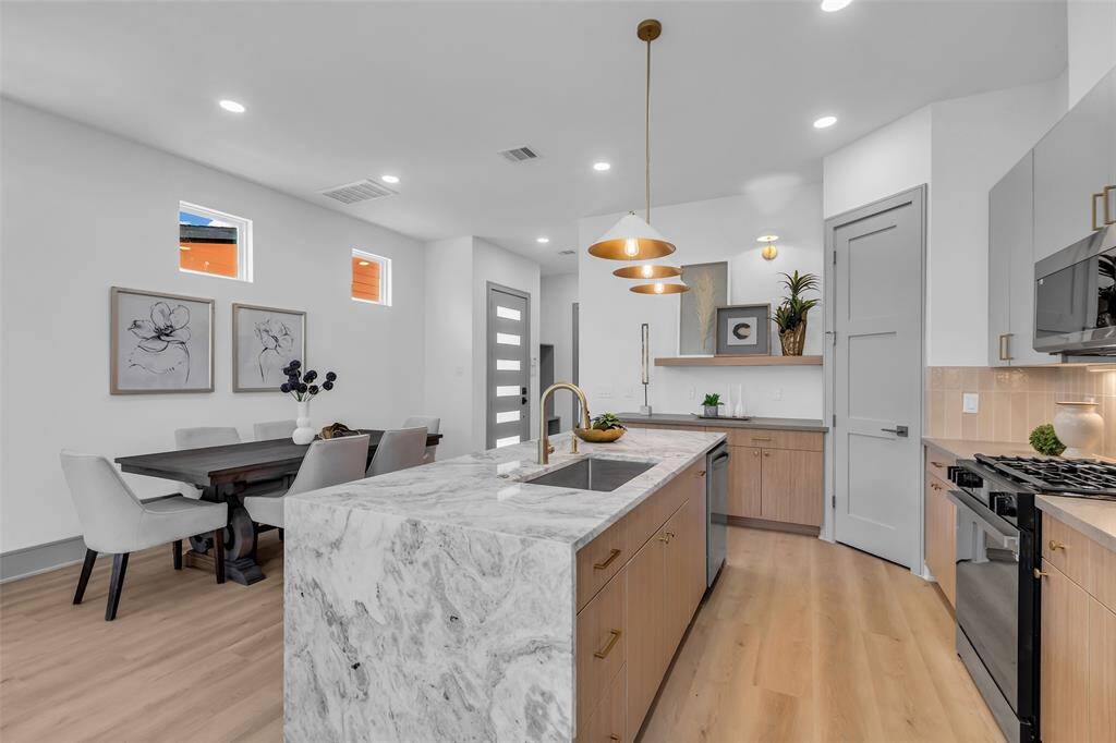 Featuring sleek designer finishes, this kitchen stands out with its striking waterfall island as the centerpiece.
