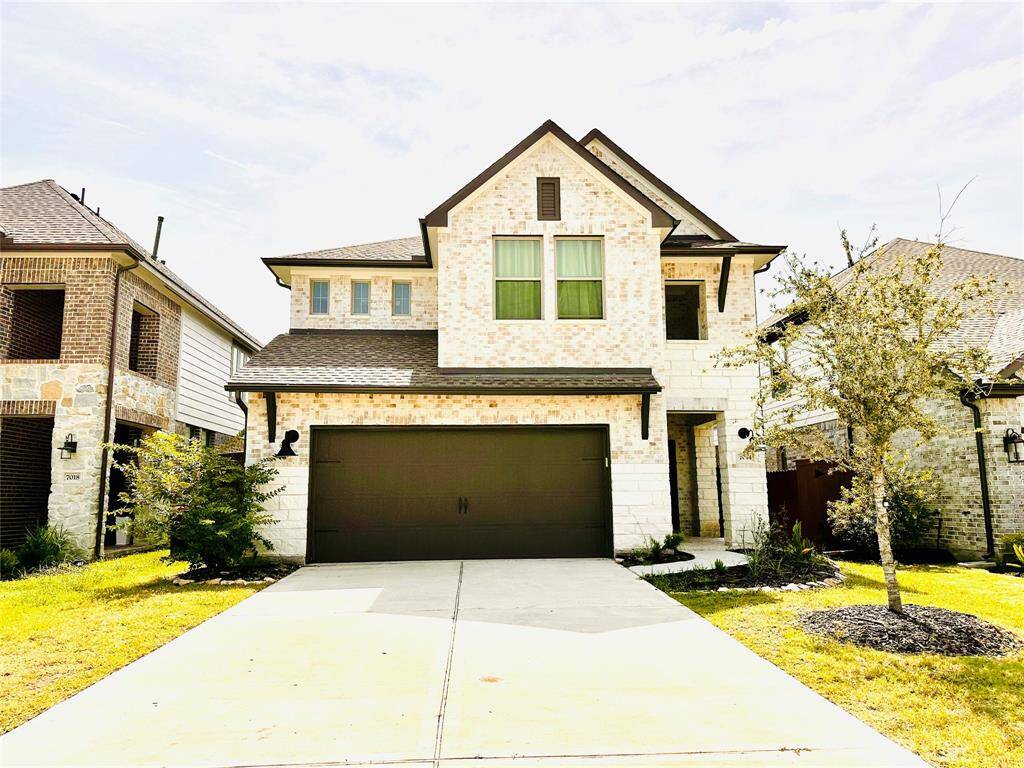 Beautiful modern two-story home featuring a mix of brick and stone facade, with a two-car garage and a neatly landscaped front yard.