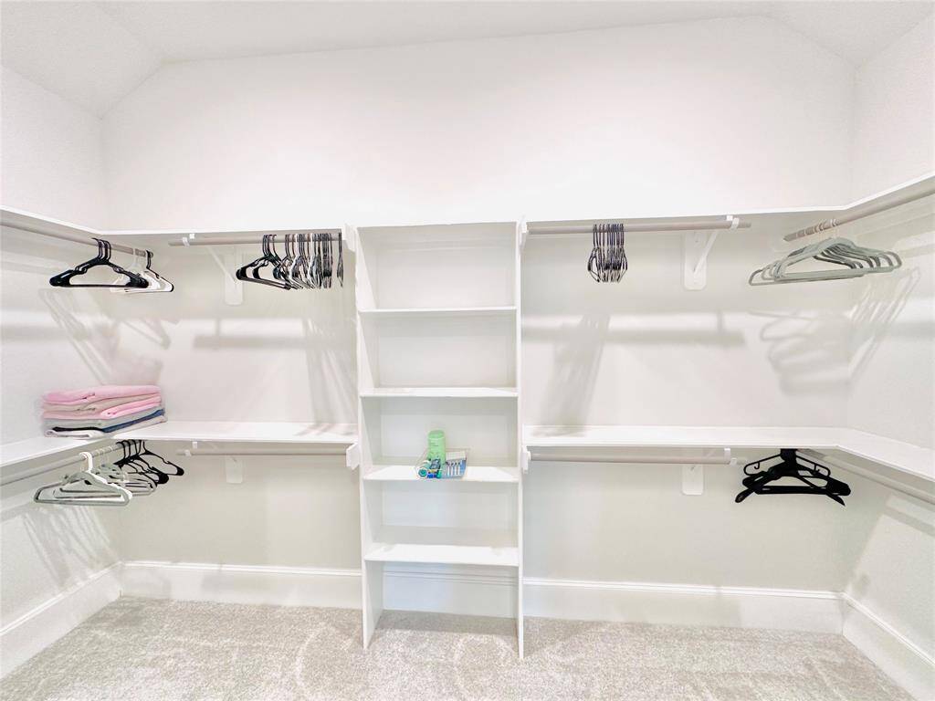 Walk-in closet with built-in shelves and hanging rods, offering ample storage for clothes and accessories.