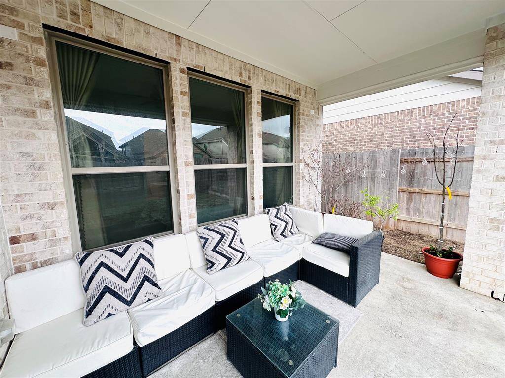 Covered patio area with comfortable seating, perfect for outdoor relaxation or entertaining guests, complemented by a view of a private fenced backyard.