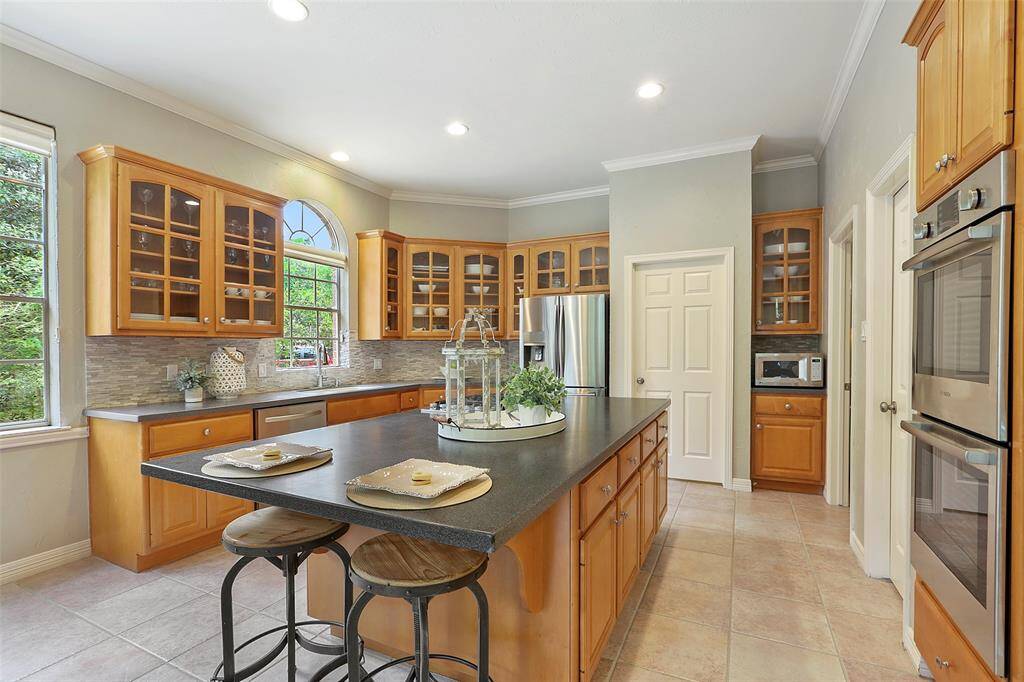 The glass front cabinets add a touch of class; casual seating at the island; double ovens and a large walk in pantry on the right. Refrigerator and microwave stay with the home.