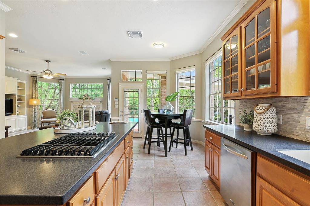 This view toward the family room shows a peek into the back yard and pool. The nice gas cooktop was upgraded in 2019.