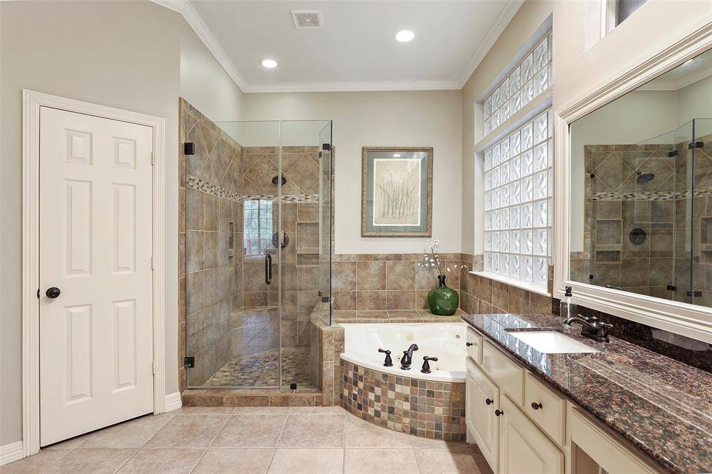 The large walk in shower has neutral tile accents and a seamless glass surround. Spa tub in the corner. Upgraded fixtures throughout.