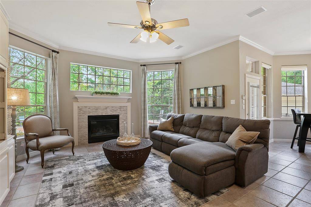The family room at the back of the home has another stacked stone fireplace. High ceilings and large windows immerse the room in light.