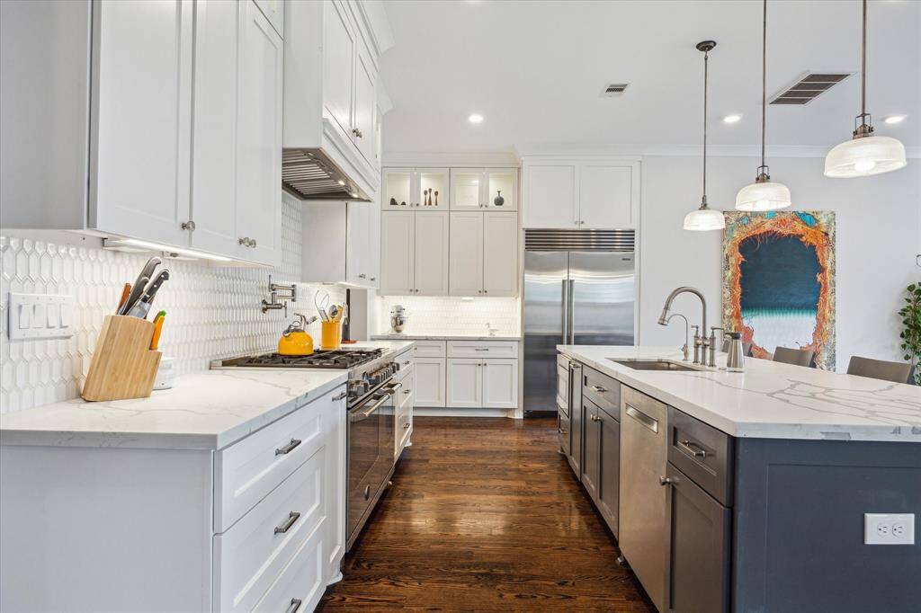 This stunning kitchen features a sub-zero refrigerator, sleek quartz countertops and abundant cabinetry- all centered around an oversized island, perfect for gathering.
