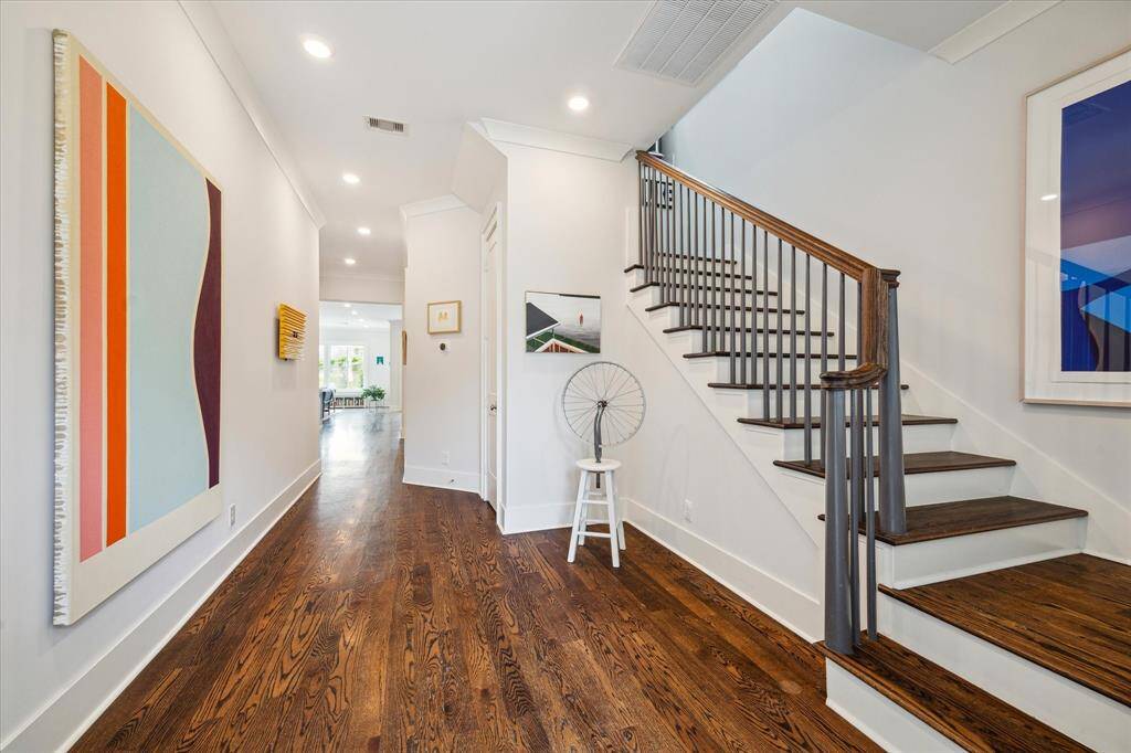 Sunlight pours through glass paneled doors and windows, illuminating the rich wood floors and creating a bright, welcoming foyer.