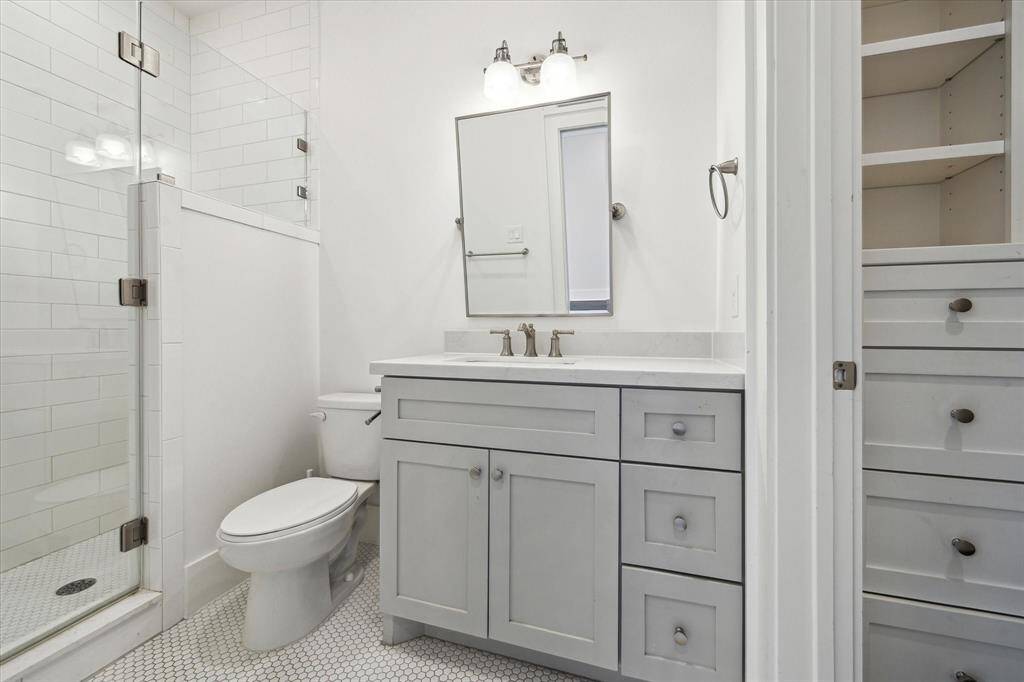 The guest en-suite bath features timeless finishes, including a walk-in shower with subway tile, a quartz topped vanity and classic hex tile flooring.