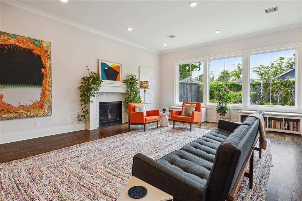 Soaring ceilings and expansive windows flood the living room with natural light, highlighting the rich wood floors.
