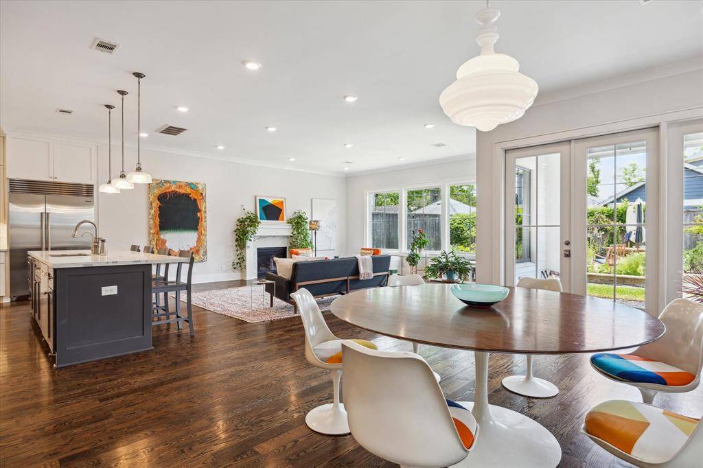 Sunlight pours into this open living and dining area, where walls of windows frame serene views of the expansive backyard and invite effortless indoor outdoor living.