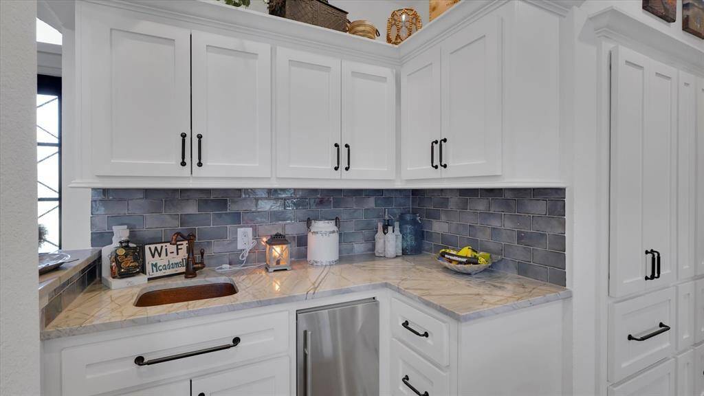 Discover the stylish wet bar with white cabinetry and a stylish backsplash that whispers sophistication. Whether you're brewing morning coffee or mixing evening cocktails, this space offers a delightful blend of functionality and elegance—perfect for inspiring those unforgettable lakefront gatherings at home.