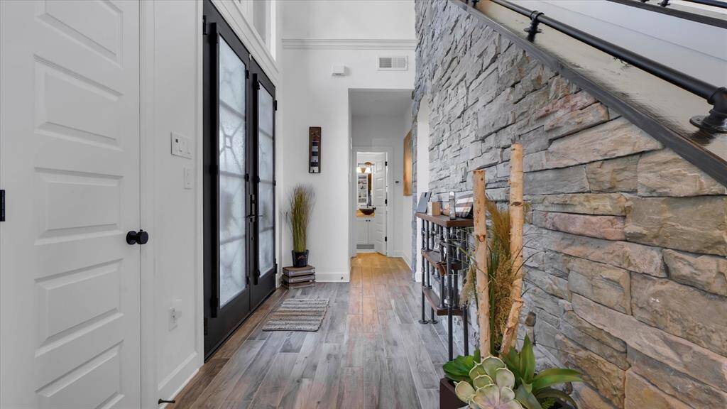 The entry provides a warm spacious greeting area with the high ceilings and stone accent wall while still allowing some privacy from the main living area.