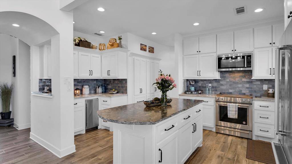Spacious island kitchen featuring granite countertops and stainless steel appliances. Love the double high cabinets that flank each side of the cooking area for additional storage area. If storage is the name of the game for the cook in your house, this kitchen is perfect.