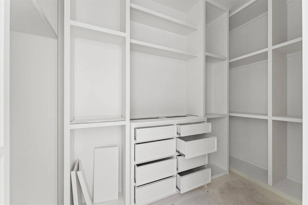 Spacious closet in primary suite with custom inset cabinetry and open shelving. *Photo taken in late April*