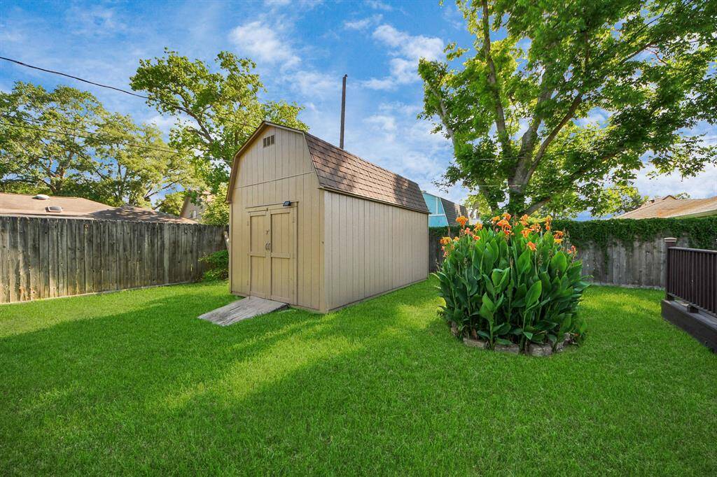 A charming storage shed offers extra space for tools or seasonal items, while the blooming flower bed adds a vibrant touch to this private yard. It’s the perfect blend of function and beauty.