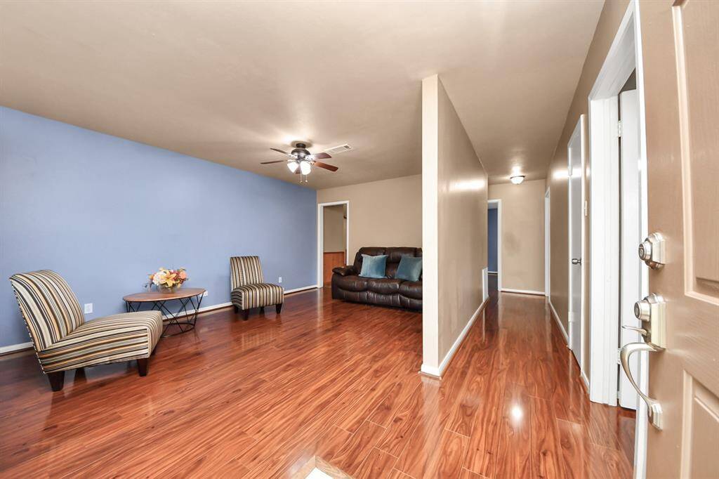 Step inside to a warm and inviting living space featuring rich wood-look flooring and a thoughtfully designed layout. The open entry flows into a spacious living area, perfect for relaxing or entertaining. A soft accent wall adds a touch of personality, while the neutral tones throughout create a cozy, move-in ready atmosphere.