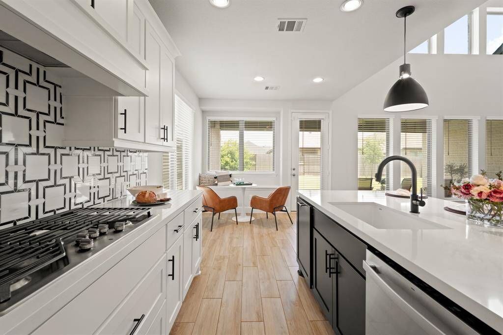 You will love the details of this kitchen! It features crown molding, a large single basin sink with sleek black faucet, black cabinet hardware, walk-in pantry, splendid textured backsplash, LED overhead lighting, contrasting cabinets, and black pendant lights.