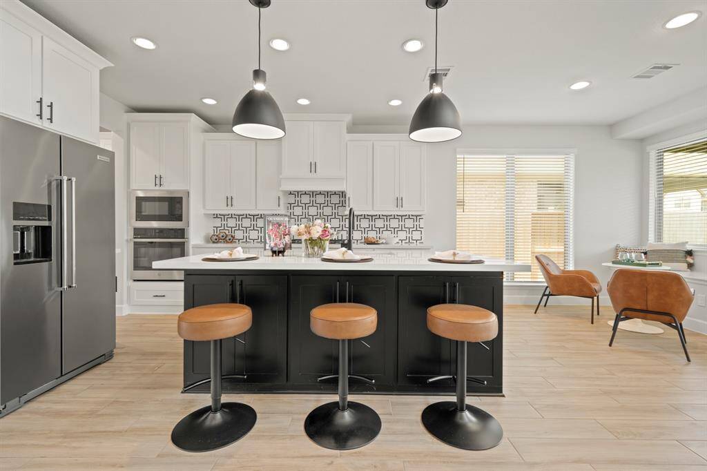 The kitchen boasts a deco wood paneled island with storage on both sides! Upgraded with built-in stainless steel appliances, a 5 burner gas cooktop, quartz countertops, and sleek white cabinets, this kitchen is ideal for cooking for the whole family or hosting holidays!