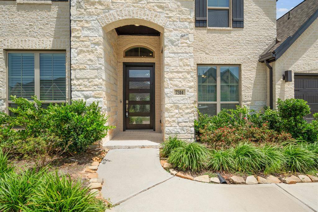 Approaching the front door you will see the beautiful brick and stone elevation, covered front porch, and an 8ft stained contemporary door! This home includes keyless entry and a smart door bell.