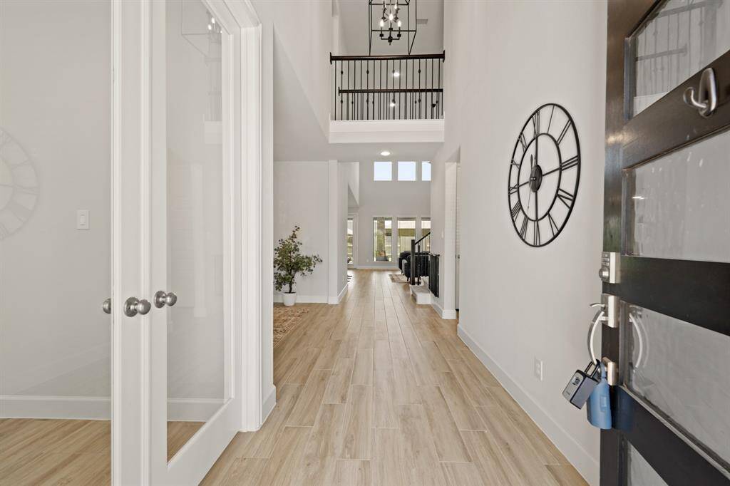 Walking in, you are greeted by a light and open space! The entryway is complete with beautiful light wood tile flooring that continues throughout the first floor into the main living areas making it easy to clean and maintain, 2 story ceilings, and a modern light fixture.