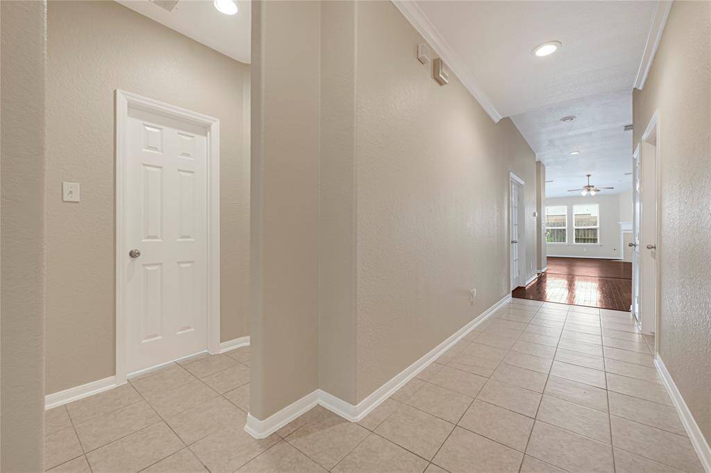Spacious entry with neutral tile flooring and crown molding leads into the heart of the home.