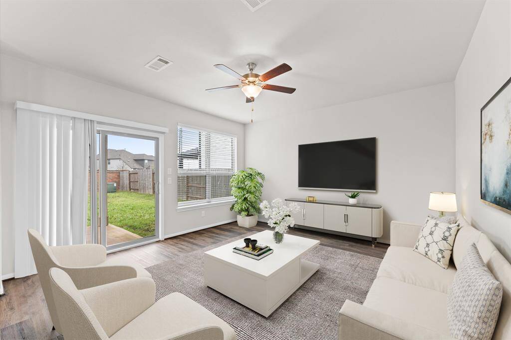 Bright and welcoming, the living area is bathed in natural light, creating a cozy and inviting atmosphere. A sliding door leads to the backyard, offering easy indoor-outdoor living.