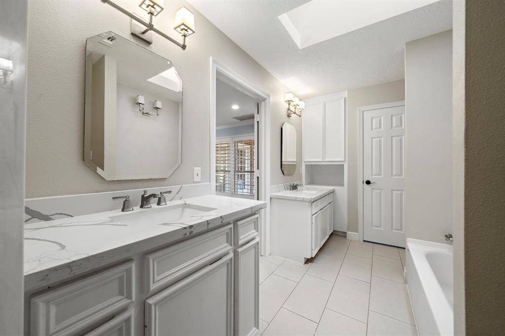 The primary bath features two vanities, a soaking tub and a standing shower.