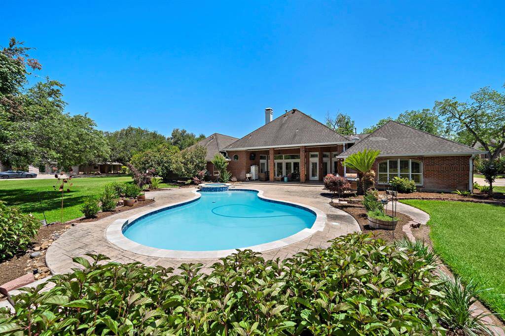 A large covered patio offers sweeping views of the sparkling pool and spa, all set against a serene water view.