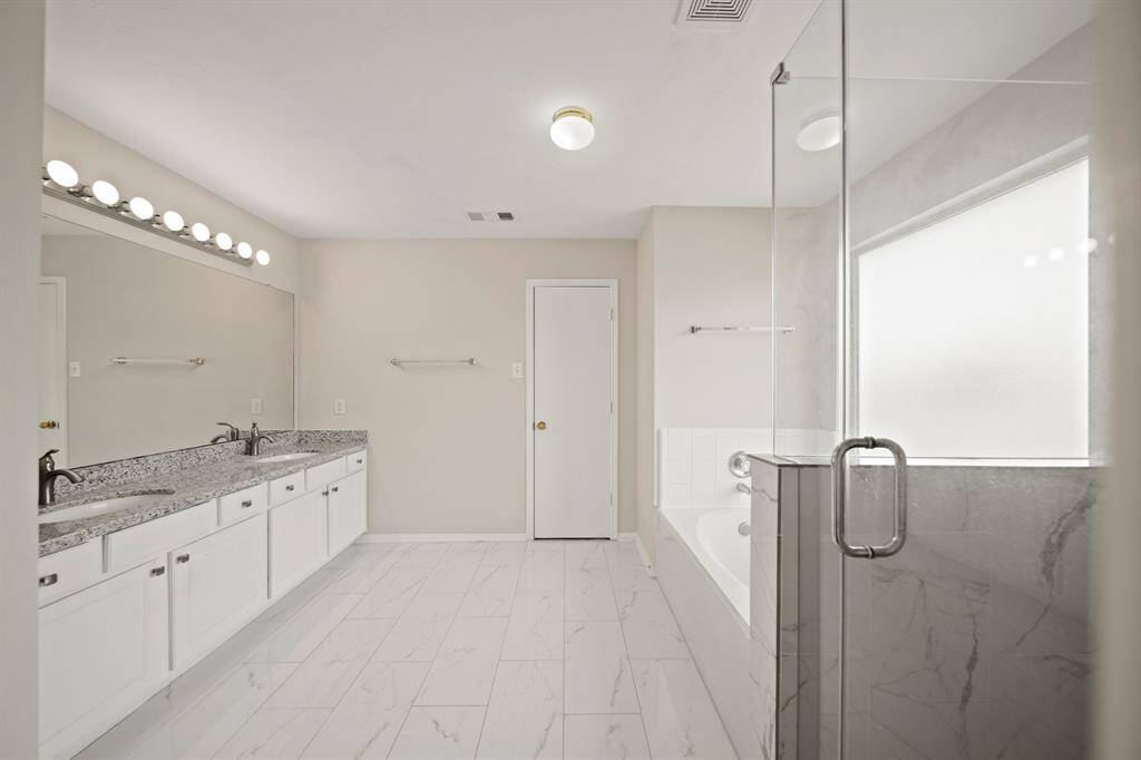 This beautiful Primary Bathroom features a gorgeous tiled walk-in shower, a large garden tub, and a frozen glass window.