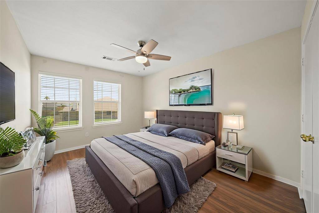 Virtually Staged: Secondary bedroom with laminate floors, a ceiling fan, neutral paint, windows with privacy blinds, and a built-in closet.