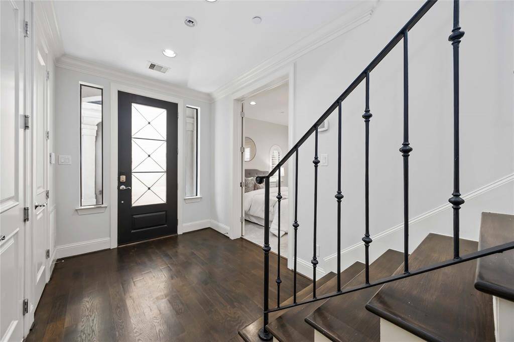 A spacious entry reveals stunning floors, a high ceiling with recessed lighting, and access to a private bedroom suite.